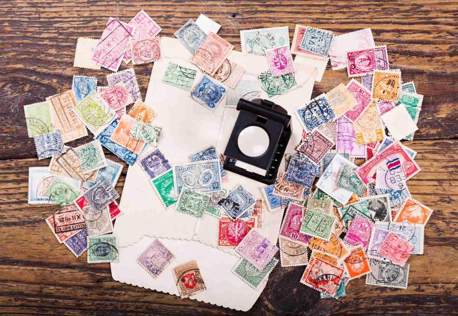 An open vintage stamp album being examined with a magnifying glass