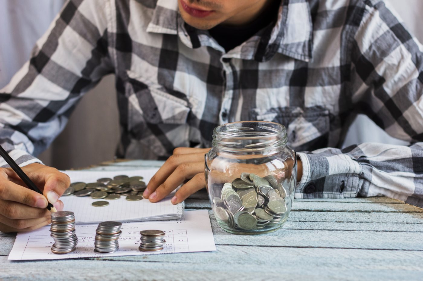 A person stacking and counting coins from a savings jar