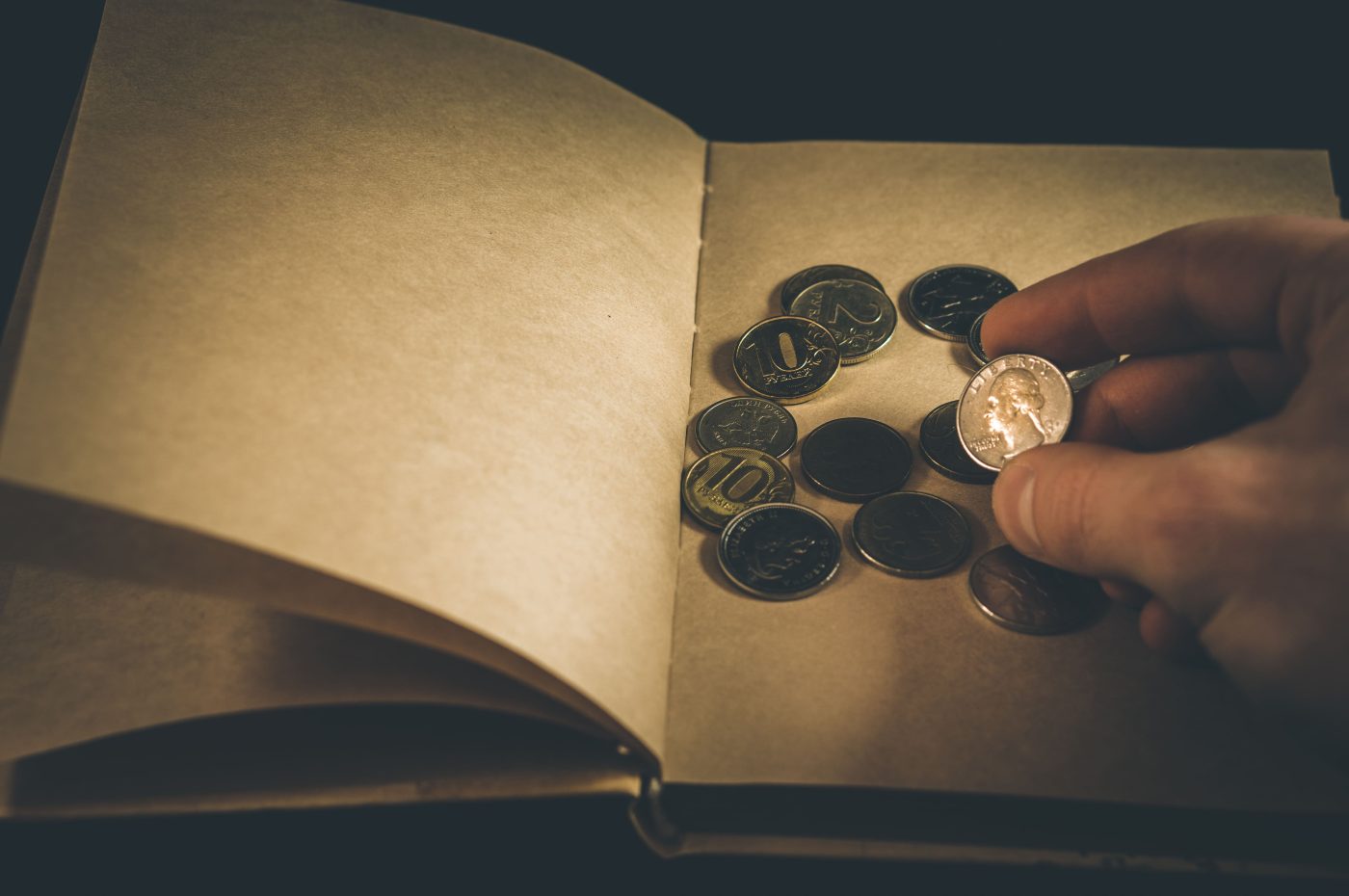 A hand placing a quarter coin into an open coin album