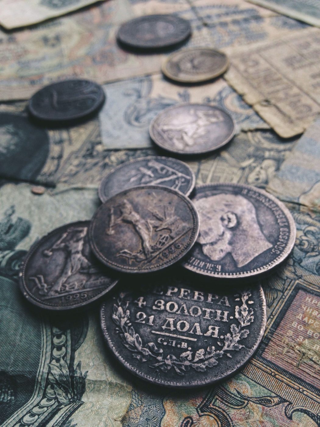 Antique silver coins resting on old banknotes