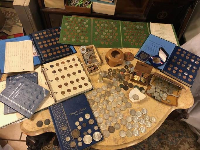 A table covered with coin albums, binders, and loose coins